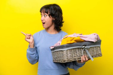 Arjantinli genç bir adam, sarı arka planda izole edilmiş bir çamaşır sepeti tutuyor. Çözümü bulmak için parmağını kaldırıyor.
