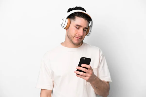 Młody Biały Człowiek Odizolowany Białym Tle Słuchanie Muzyki Telefonu Komórkowego — Zdjęcie stockowe