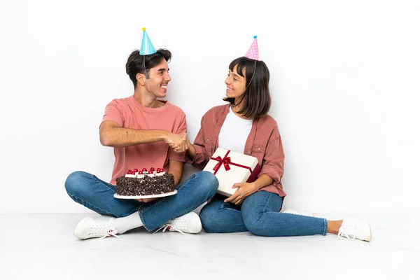 Jovem Casal Misto Comemorando Aniversário Sentado Chão Isolado Fundo Branco — Fotografia de Stock