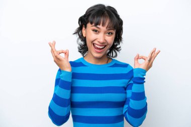 Beyaz arka planda izole edilmiş genç Arjantinli kadın iki eliyle tamam işareti gösteriyor.