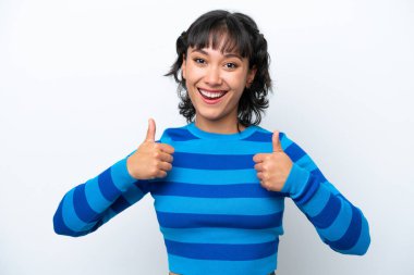 Beyaz arka planda izole edilmiş genç Arjantinli kadın baş parmak hareketi yapıyor.