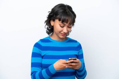 Beyaz arka planda izole edilmiş genç Arjantinli kadın cep telefonuyla mesaj gönderiyor.