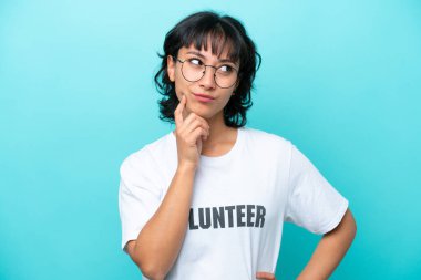 Genç gönüllü Arjantinli kadın mavi arka planda izole edilmiş.