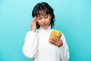 Elinde kızarmış cips tutan genç Arjantinli kadın mavi arka planda başağrısı ile izole edilmiş.