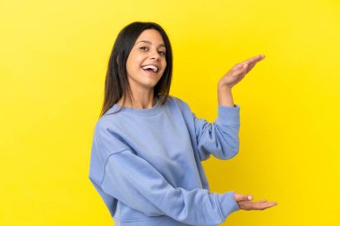 Sarı arka planda izole edilmiş beyaz bir kadın ilan vermek için kopyalama alanı tutuyor.