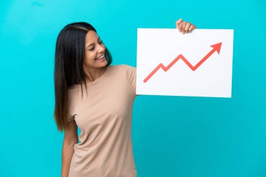 Arkaplanda mutlu bir ifadeyle büyüyen bir istatistik ok sembolü taşıyan bir tabela tutan izole edilmiş genç bir kadın.