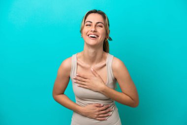 Mavi arka planda izole edilmiş genç beyaz kadın çok gülümsüyor.