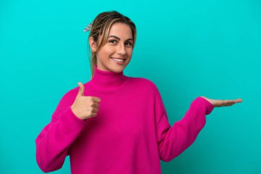 Mavi arka planda izole edilmiş beyaz bir kadın. Avucunun içinde hayali bir şey tutuyor. Bir ilan vermek için.