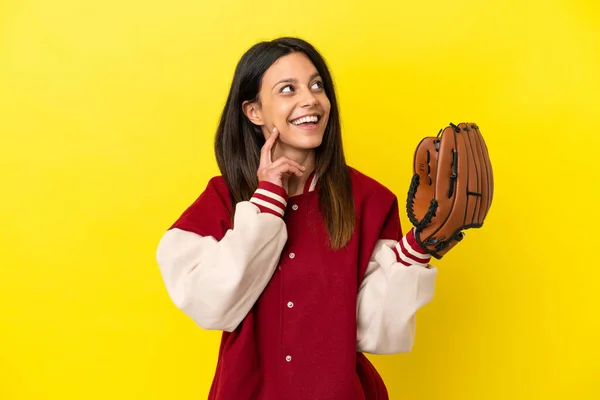 黄色の背景に隔離された野球をしている若い白人女性は 上を見ながらアイデアを考えます — ストック写真