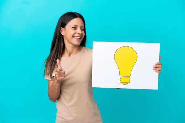 Young Woman Isolated Background Holding Placard Bulb Icon Pointing Front — Zdjęcie stockowe