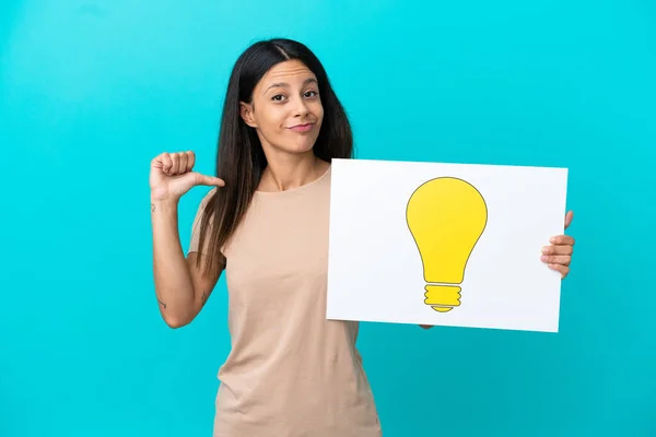 Young Woman Isolated Background Holding Placard Bulb Icon Proud Gesture — Stock Photo, Image