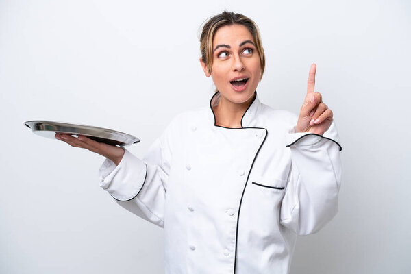 Young chef woman with tray isolated on white background thinking an idea pointing the finger up