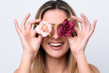 Beyaz arka planda izole edilmiş beyaz bir kadın elinde mutlu bir ifadeyle çiçekleri tutuyor. Portreyi kapat