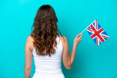İngiliz bayrağı taşıyan beyaz bir kadın mavi arka planda izole edilmiş.