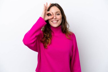 Beyaz arka planda izole edilmiş genç beyaz kadın parmaklarıyla tamam işareti gösteriyor.