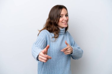 Beyaz arka planda izole edilmiş genç beyaz kadın şaşırmış ve ön tarafı işaret ediyor.