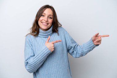 Beyaz arka planda izole edilmiş genç beyaz kadın şaşırmış ve işaret ediyor.