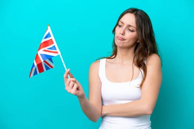 İngiliz bayrağı taşıyan beyaz bir kadın mavi arka planda hüzünlü bir ifadeyle izole edilmiş.