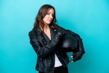 Motosiklet kasklı genç beyaz kadın mavi arka planda izole edilmiş gururlu ve kendinden memnun.