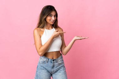 Pembe arka planda izole edilmiş genç beyaz kadın bir ilan vermek için avucunun içinde hayali bir fotokopi makinesi tutuyor.