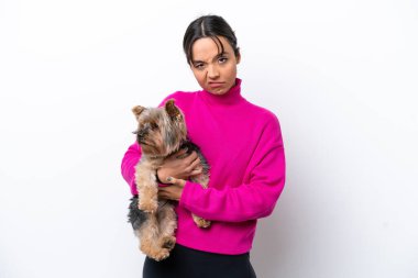 Beyaz arka planda üzgün bir ifadeyle bir köpeği tutan genç İspanyol kadın.