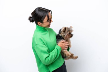 Young hispanic woman holding a dog isolated on white background with happy expression