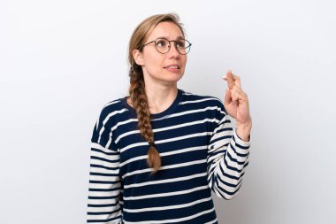 Beyaz arka planda izole edilmiş beyaz tenli genç bir kadın parmaklarını çapraz yapıp en iyisini diliyor.