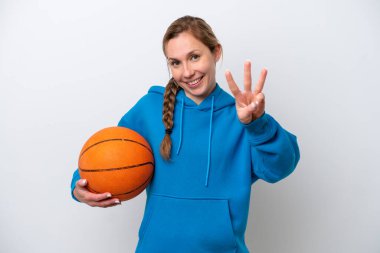 Beyaz arka planda basketbol oynayan beyaz kadın mutlu ve parmaklarıyla üçe kadar sayıyor.