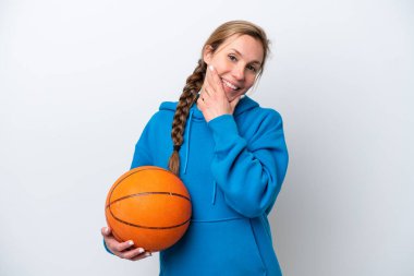 Beyaz arka planda basketbol oynayan beyaz kadın mutlu ve gülümsüyor.