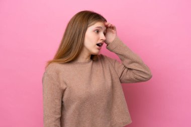 Genç Rus kız, pembe arka planda yalıtılmış, sürpriz bir ifadeyle yan yana bakarken...