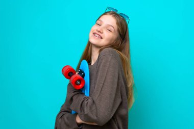 Genç kaykaycı kız mavi arka planda izole edilmiş.