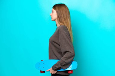 Genç Rus kız mavi arka planda paten kayarak izole edilmiş.