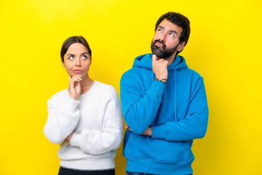 Kafkasyalı genç çift sarı arka planda izole edilmiş duruyor ve bir fikir düşünüyorlar.