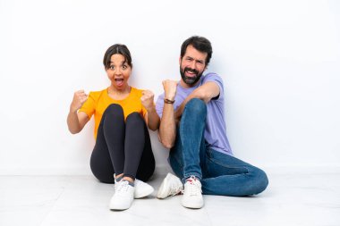 Beyaz arka planda izole bir şekilde yerde oturan beyaz bir çift zaferi kutluyor.