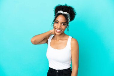 Mavi arka planda yalnız yaşayan genç Latin kadın gülüyor.