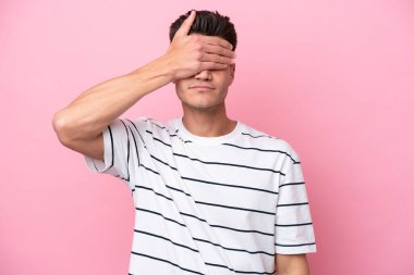 Pembe arka planda izole edilmiş genç, beyaz bir adam gözlerini elleriyle kapatıyor. Bir şey görmek istemiyorum.