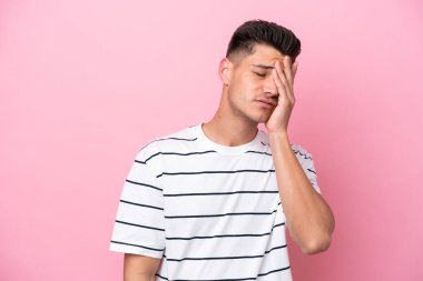 Kafkasyalı genç adam pembe arka planda izole edilmiş, baş ağrısı var.