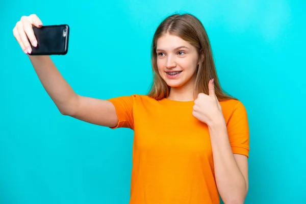 Nastoletnia Rosjanka Odizolowana Niebieskim Tle Robi Selfie Telefonem Komórkowym — Zdjęcie stockowe