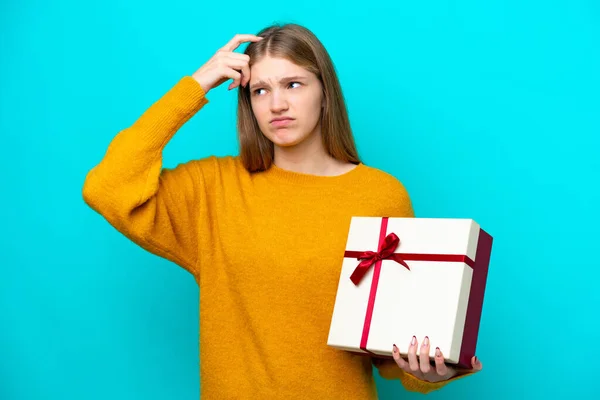 Teenager Russian Girl Holding Gift Isolated Blue Background Having Doubts — Stock Photo, Image