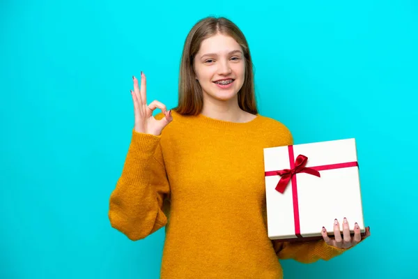 Teenager Russian Girl Holding Gift Isolated Blue Background Showing Sign — Stockfoto