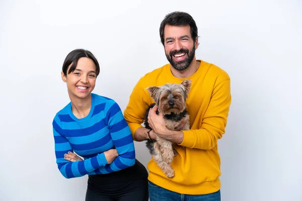 Young hispanic woman holding a dog isolated on white background keeping the arms crossed while smiling