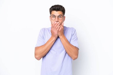 Beyaz arka planda izole edilmiş genç beyaz bir adam elleriyle ağzını kapatıyor.