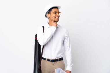 Miğferi olan ve elinde izole edilmiş beyaz arkaplan üzerinde planlar tutan Afrikalı Amerikalı mimar bir fikir ararken