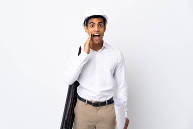 Miğferli Afrikalı Amerikalı mimar, izole edilmiş beyaz arka plan üzerinde planları tutuyor ve şaşırmış ve şok olmuş bir yüz ifadesi var.