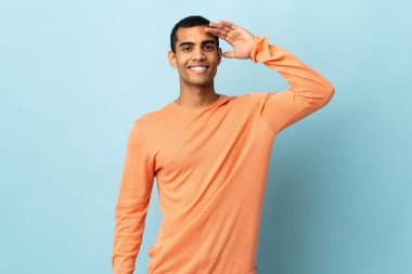 Afro-Amerikalı bir adam izole edilmiş arka planda mutlu bir ifadeyle selamlıyor.