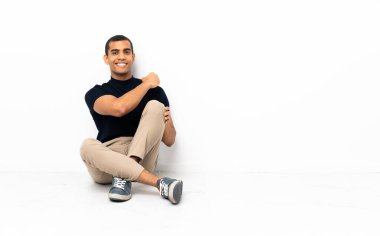 Afro-Amerikalı bir adam yerde oturmuş zaferi kutluyor.