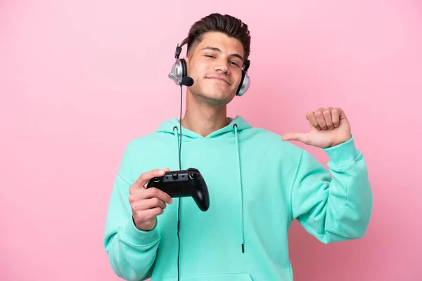 若いですハンサムな白人男性再生とともにAビデオゲームコントローラ孤立ピンクの背景誇りと自己満足 — ストック写真