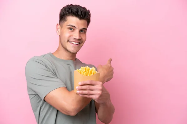 Jonge Blanke Man Met Gebakken Chips Geïsoleerd Roze Achtergrond Wijzend — Stockfoto