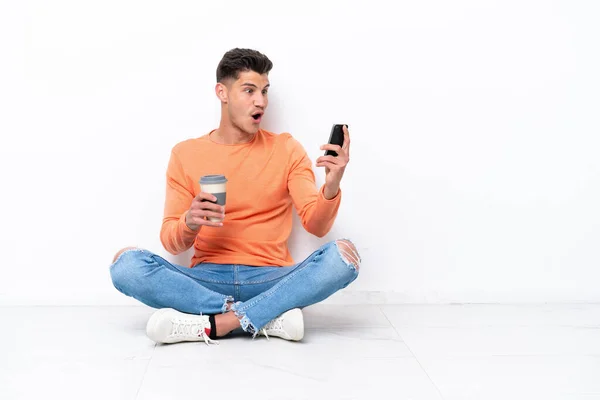 Junger Mann Sitzt Isoliert Auf Dem Boden Und Hält Kaffee — Stockfoto