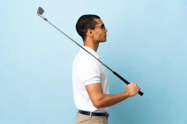 非洲裔美国人在与外界隔绝的蓝色背景上打高尔夫球 — 图库照片